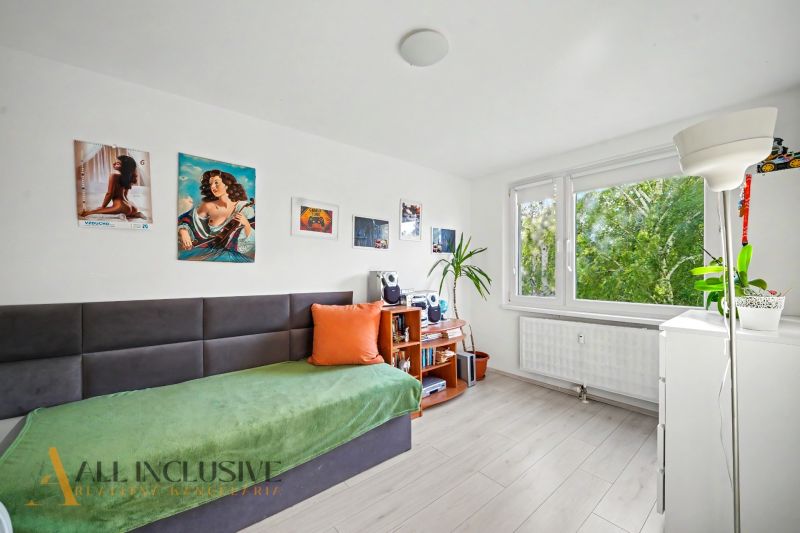A room in a 3-room apartment with comfortable seating, wall decorations, and a large window.