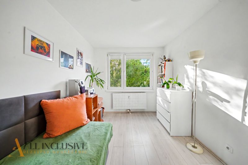 A bright room in a 3-room apartment, wooden decor flooring, simple furniture and decorations.