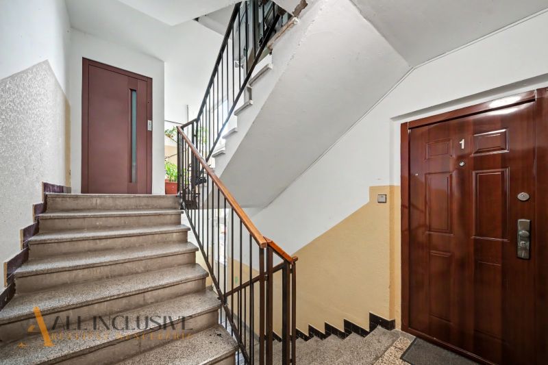 A staircase with a wooden railing and entrance doors in a 3-room apartment.