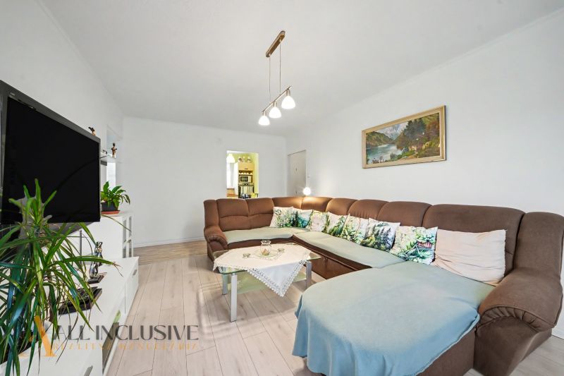 Living room in a 3-room apartment with a sofa, television, and a wooden decor floor.