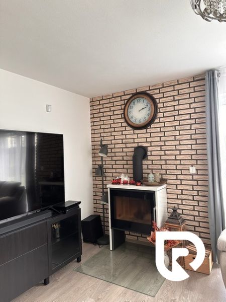 Living room in a family house with a fireplace, brick cladding, and a wooden decor floor.