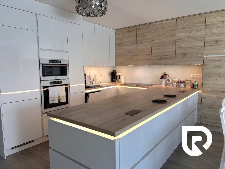 A kitchen in a family house with white cabinets and a wood-patterned floor.