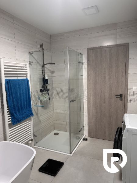 Bathroom with a shower, bathtub, washing machine, and towel in a family house.