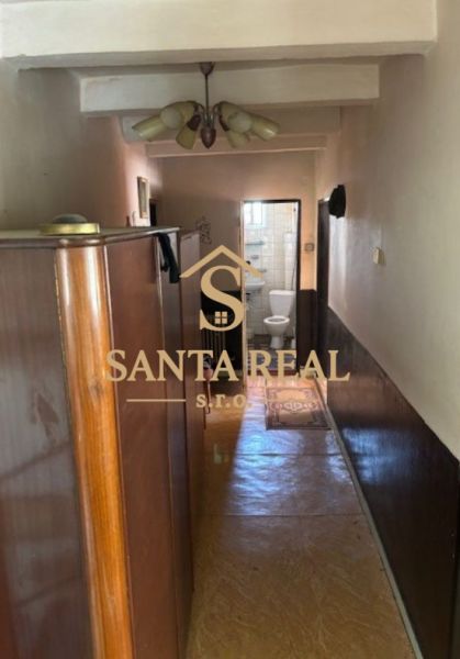 A narrow hallway in a family house with a view of the bathroom, wooden decor flooring.