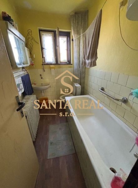 A bathroom in a family house with a bathtub and a wooden decor floor.