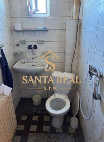 Bathroom in a family house with a sink, shower, and toilet, with soft tiles on the walls.