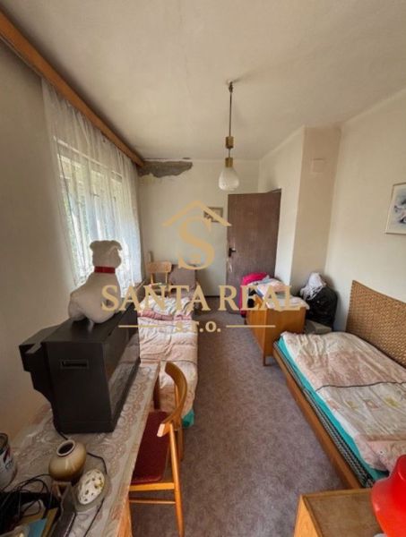 A room in a family house with beds, a dresser, a television, and curtains.