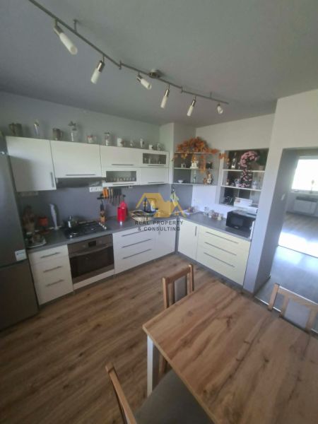 A kitchen with white cabinets and a wood-patterned floor in a 3-room apartment.