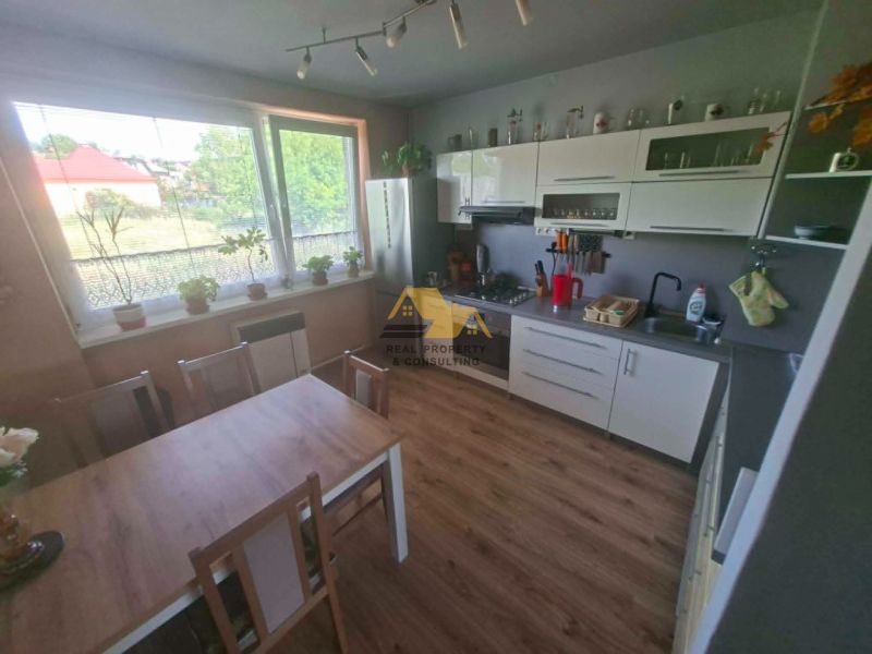 A kitchen with a wooden decor floor and a dining table in a 3-room apartment.