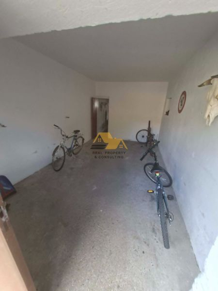 A garage with bicycles in a 3-room apartment, simple white walls and a concrete floor.