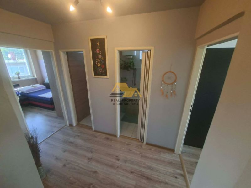 A hallway in a 3-room apartment with a wooden decor floor and a view into the bedroom.