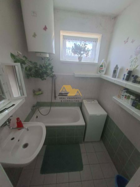 Bathroom with a bathtub, sink, washing machine, and window, 3-room apartment.