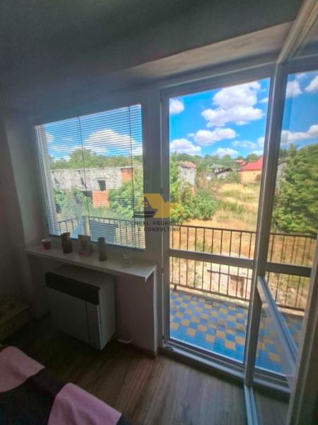 A room with a balcony, wooden decor flooring, and a garden view in a 3-room apartment.