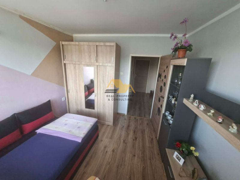 Bedroom with a bed, wardrobe, and display cabinet in a 3-room apartment, floor with wood decor.