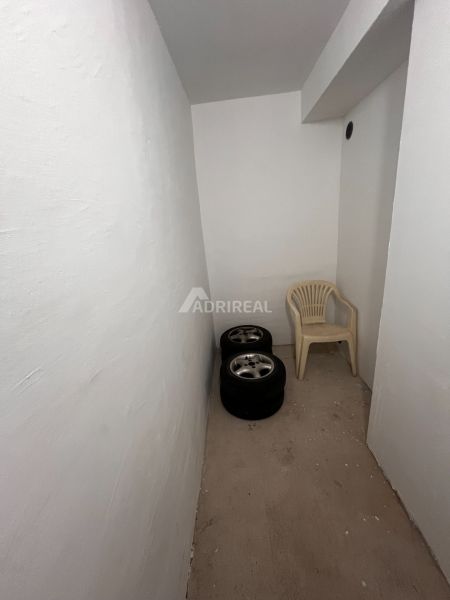 A small room with white walls in a 2-room apartment with tires and a plastic chair.