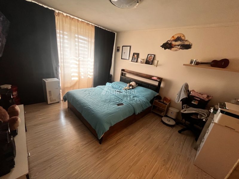 A bedroom with a bed and a wooden decor floor in a two-room apartment.