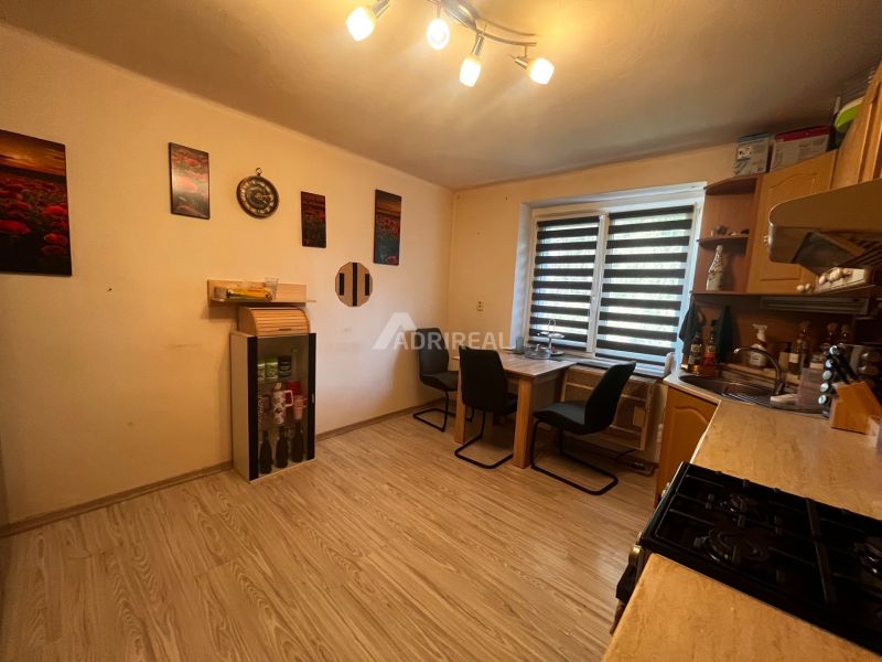 A kitchen in a 2-room apartment with a wooden decor floor and furniture.