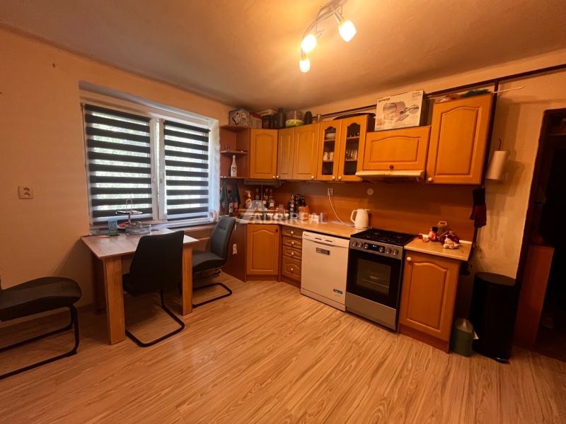 Kitchen with dining table; 2-room apartment with wood-patterned flooring.