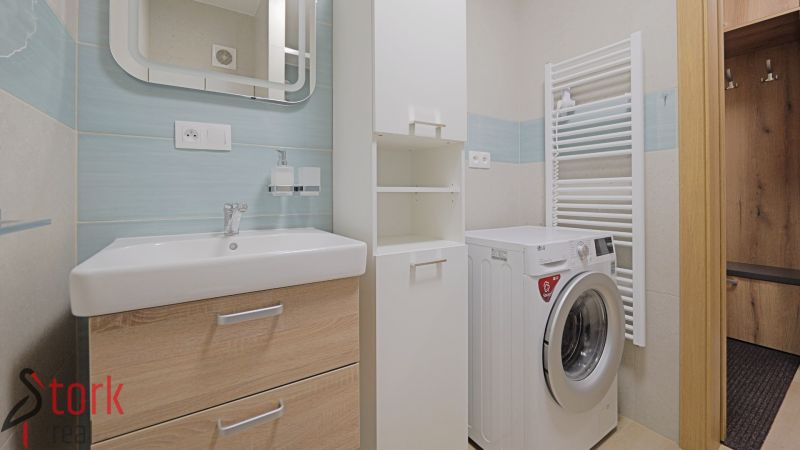 Bathroom with a washing machine and a sink in the interior of a studio apartment with blue tiles.