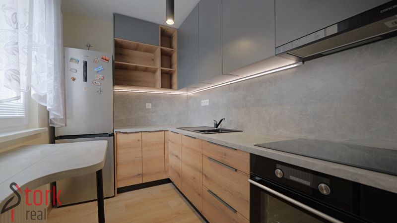 A kitchen in a studio apartment with a wood-patterned floor and gray cabinets.