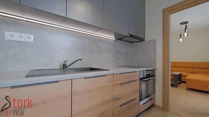 A kitchen in a studio apartment with a wood-patterned floor and built-in appliances.