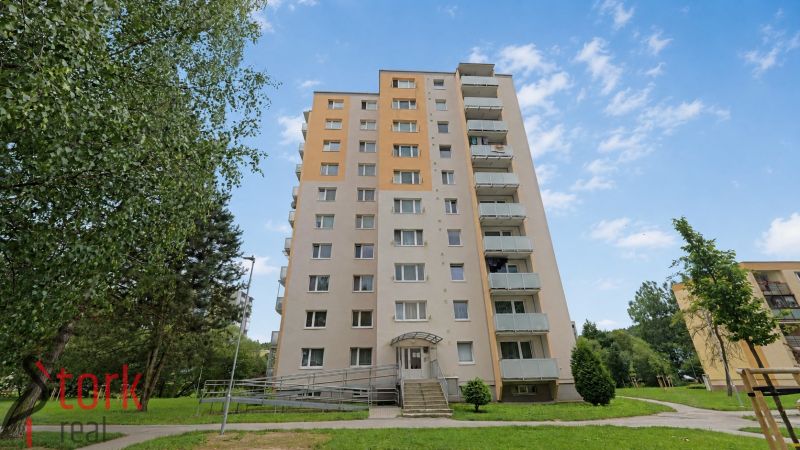 A high-rise building on SNP Street in Považská Bystrica surrounded by greenery.