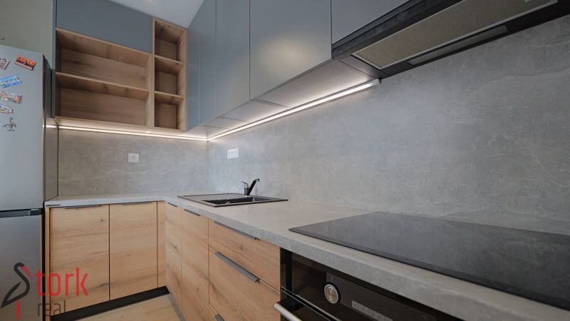 A kitchen with wooden cabinets and built-in appliances in a studio apartment.