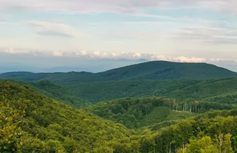 Mountain forests and hills surrounding agricultural and forest lands near Veľké Ozorovce.