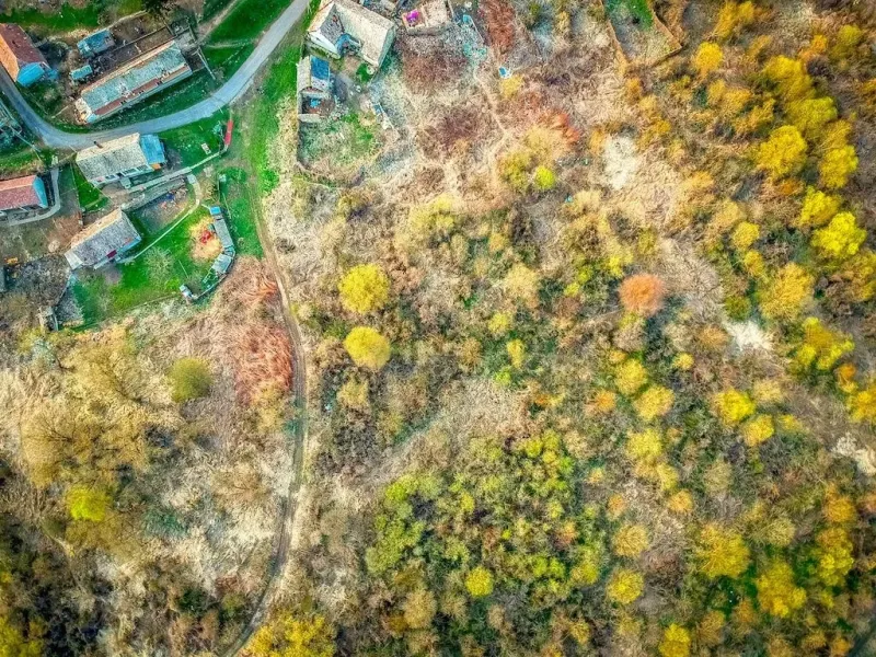 Aerial view of plots - housing in the village of Muľa, surrounded by greenery and a road.