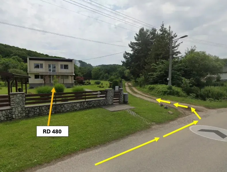 A family house and gardens in Bystré by the road with signposts.