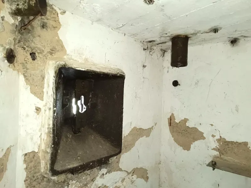 Plastered interior of a peculiar property with a metal hatch in the wall.