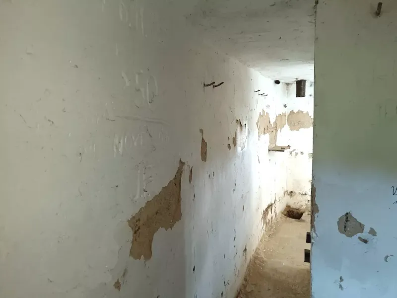 Abandoned narrow space with damaged walls, falling into the category of peculiar properties.