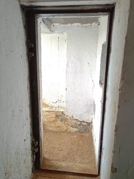 A narrow concrete hallway in Special Properties with light walls and a brown floor.