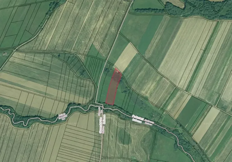 Aerial view of agricultural and forest lands around Podhorany with a river flowing through the landscape.
