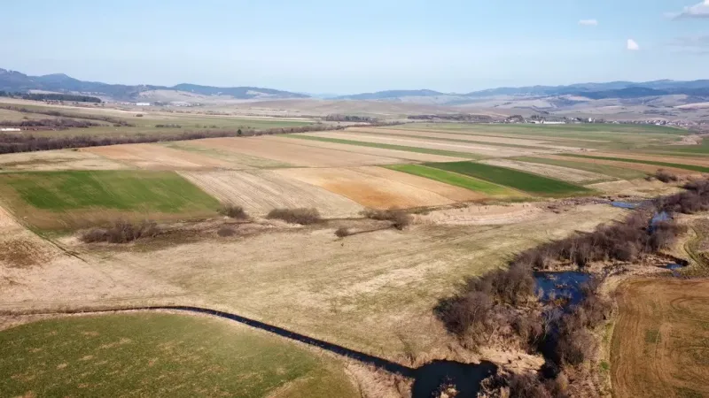 Agricultural and forest lands in Podhorany with a river between the fields and the mountain range.