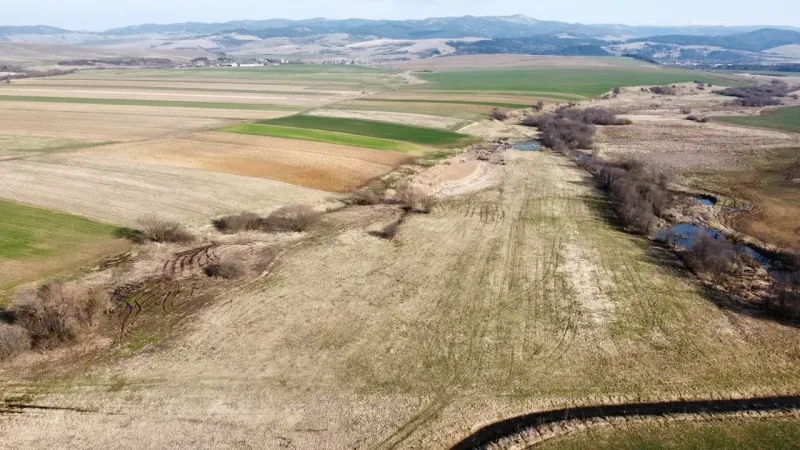Agricultural and forest lands in Podhorany with meadows, fields, and surrounding hills.