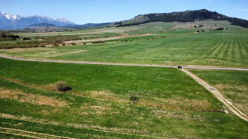 Beautiful agricultural and forest lands in Podhorany with a view of the mountains, road, and meadows.
