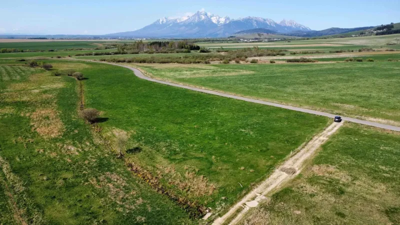 Agricultural and forest lands in Podhorany, with a road and distant mountains on the horizon.