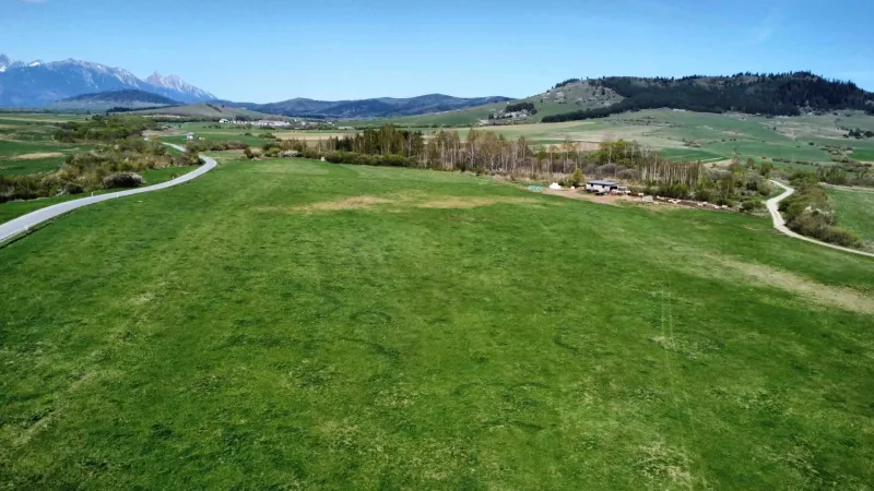 Panorama of agricultural and forest lands in Podhorany with a mountain background and a road.