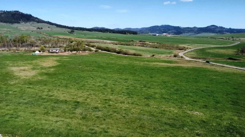 The landscape in Podhorany, agricultural and forest lands with meadows, a road, and surrounding mountains.