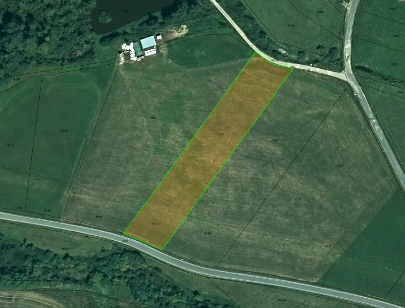 Aerial view of agricultural and forest land in Podhorany with a marked parcel.