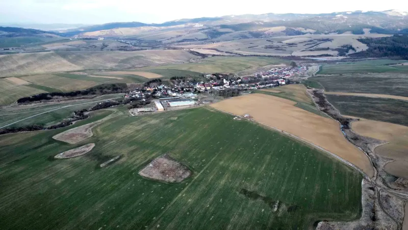 View of agricultural and forest lands in Podhorany surrounded by hills and fields.