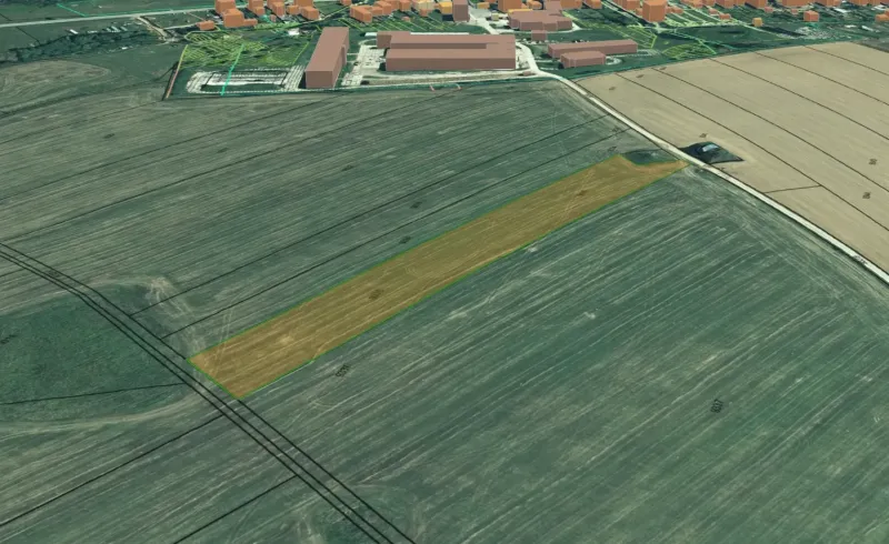 Agricultural and forest land in Podhorany with a marked field near the urbanized area.