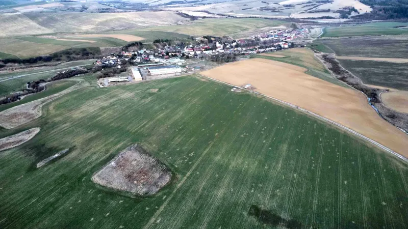 Aerial view of agricultural and forest lands around Podhorany with the village in the background.