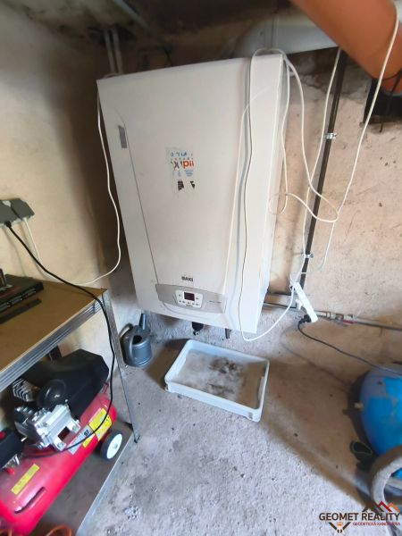 Boiler in the basement area of the family house, next to the compressor and the shelf.