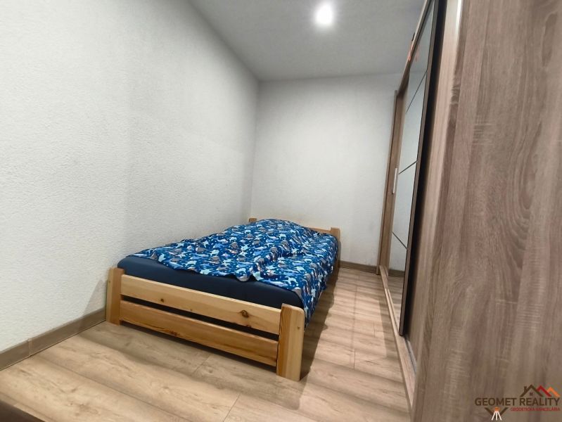 Bedroom in a family house with a bed, wardrobe, and wooden decor flooring.