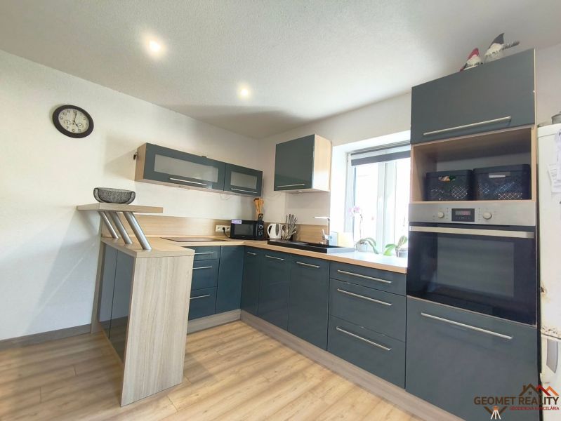 A kitchen in a family house with dark cabinets and a wood-patterned floor.