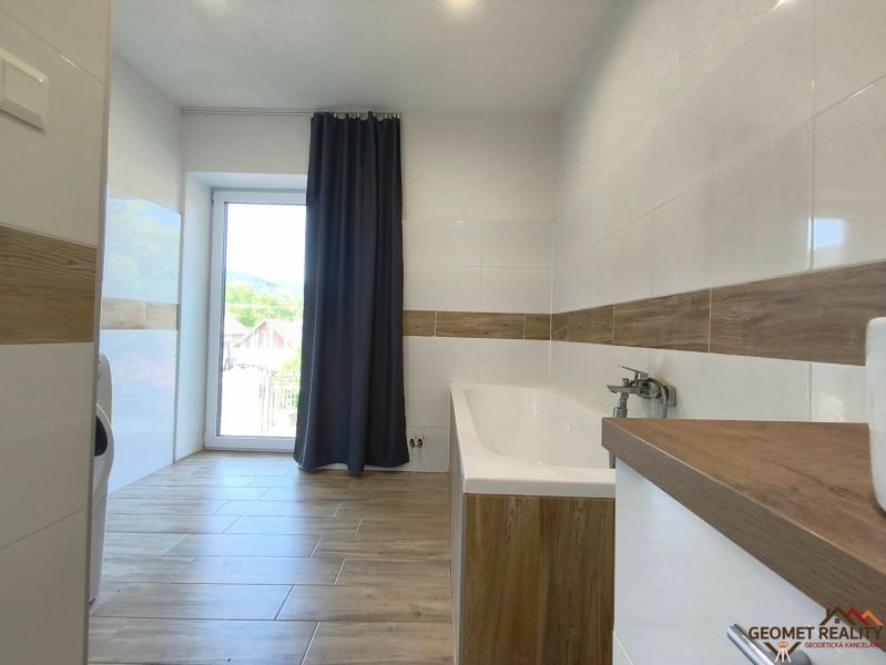 A bathroom with a bathtub and a wooden decor floor in a family house.