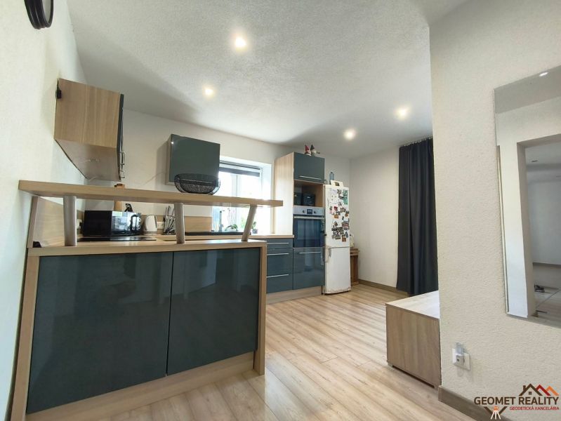 A kitchen in a family house with a wooden decor floor, light walls, and modern equipment.