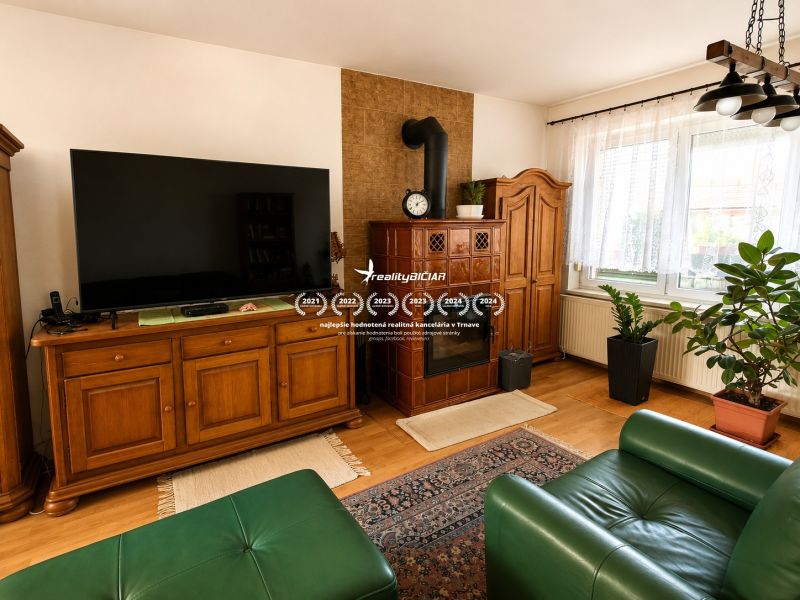 Living room in a family house with a tiled stove, television, and wooden decor.